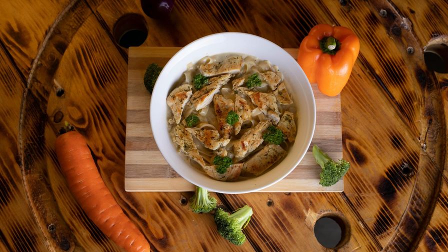 Pollo con coliflor cremosa servido en un plato con presentación sencilla.