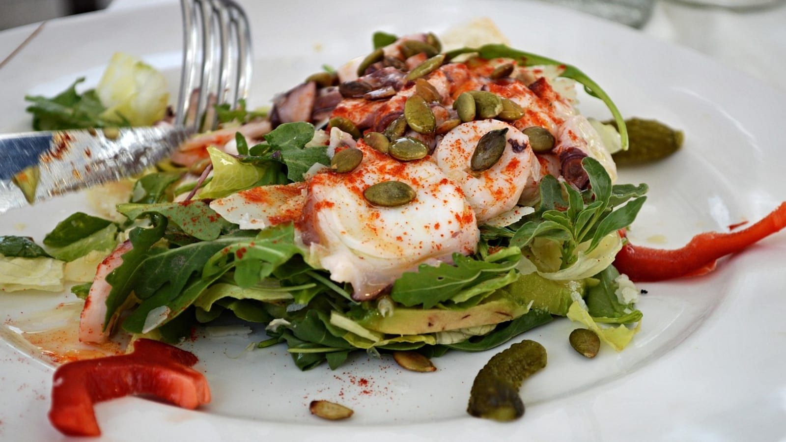 Pescado blanco con ensalada servido en un plato con presentación sencilla.