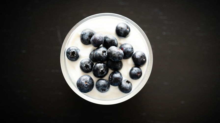 Yogur natural con frutos rojos servido en un plato con presentación sencilla.