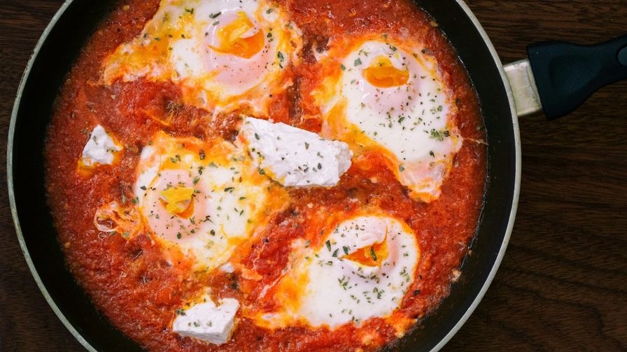 Huevos cocinados con tomate en una sartén.