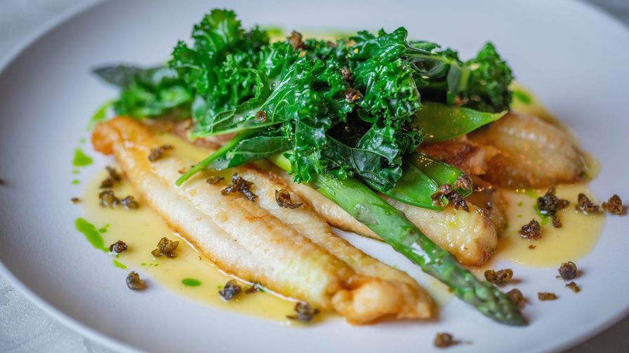 Pescado blanco con espárragos servido en un plato con presentación sencilla.