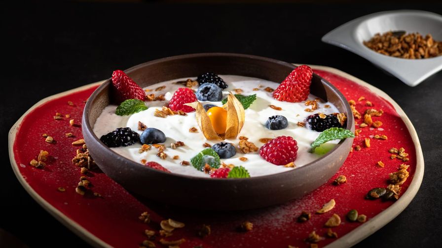 Yogur con frutos rojos y nueces servido en un plato con presentación sencilla.
