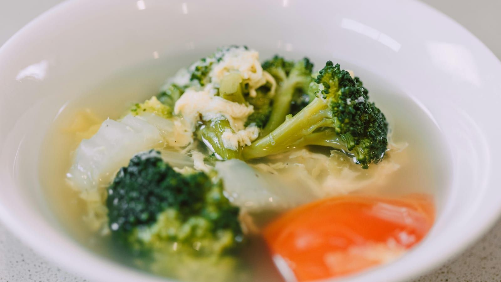 Sopa de verduras con huevo servido en un plato con presentación sencilla.