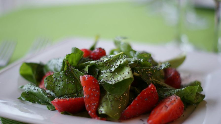 Ensalada de espinacas y fresas servida en un plato blanco.