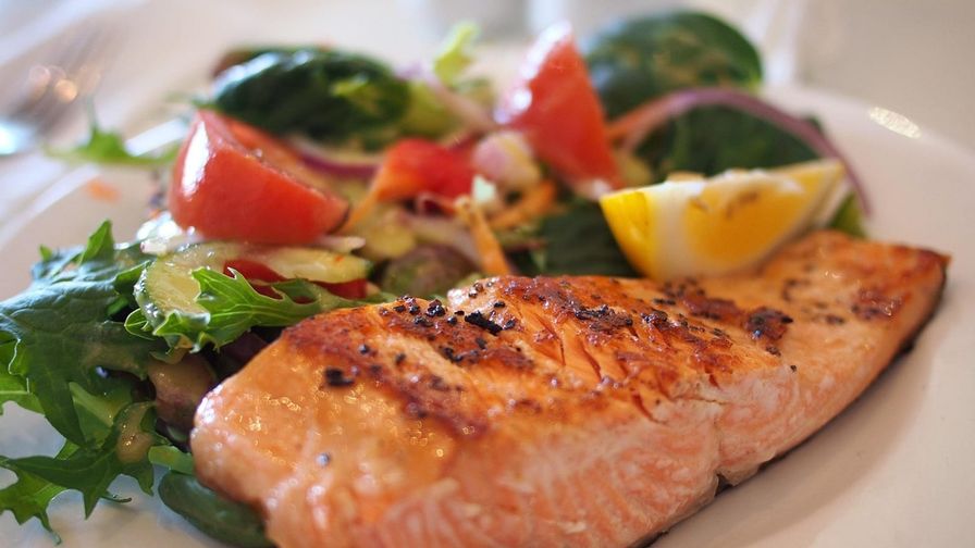 Salmón a la plancha con frutos rojos servido en un plato con presentación sencilla.