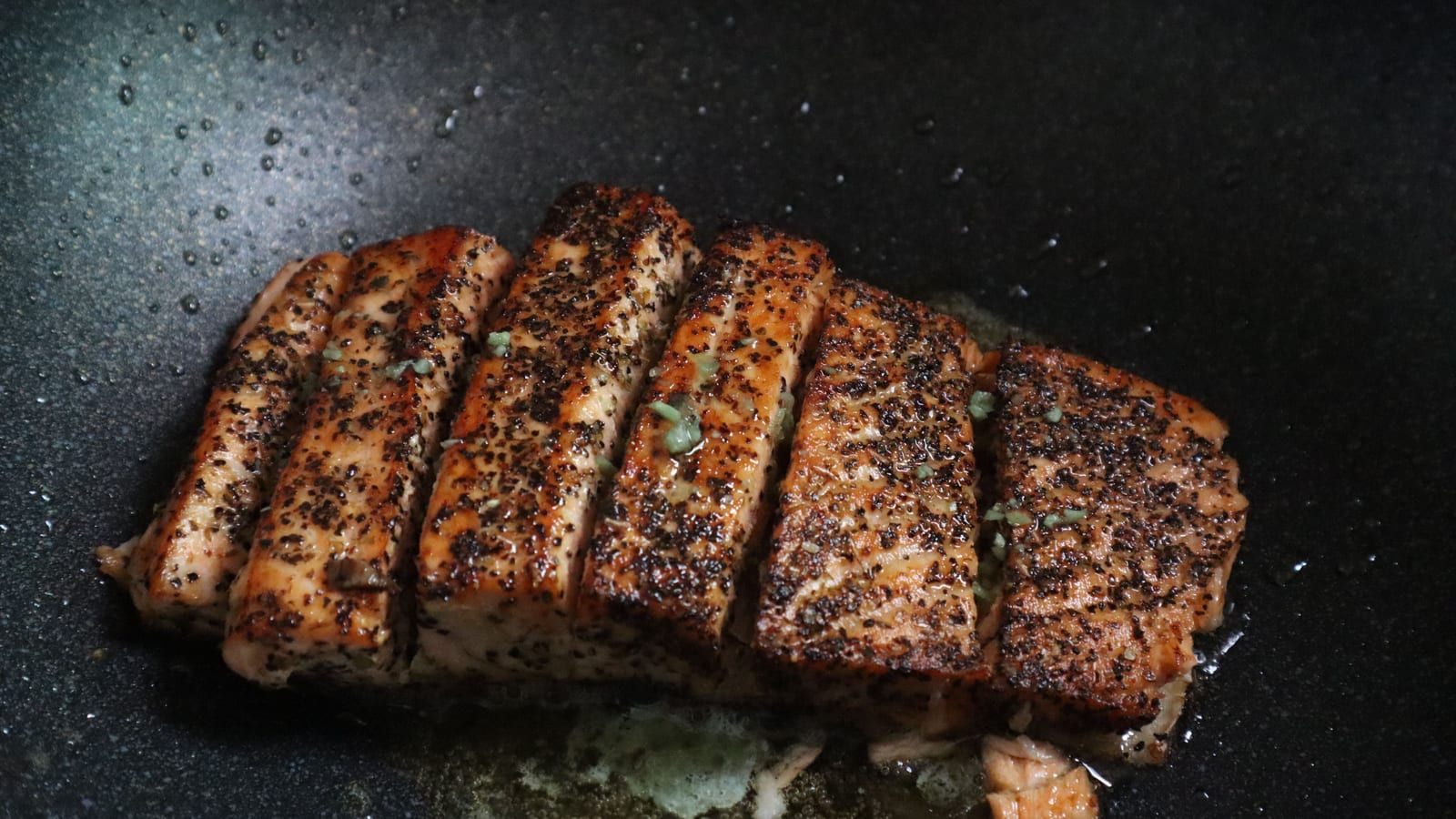 Salmón con costra de hierbas servido en un plato con presentación sencilla.