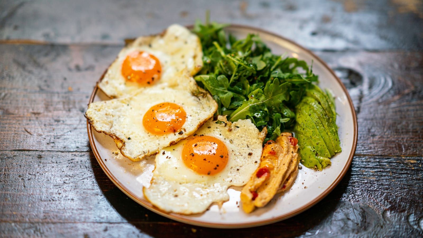 Huevos con aguacate y espinacas servido en un plato con presentación sencilla.
