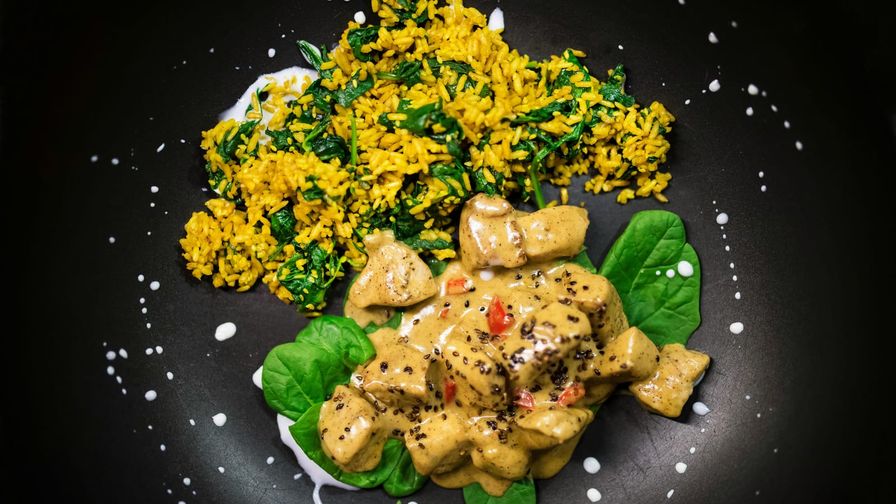 Pollo al curry suave servido en un plato oscuro.